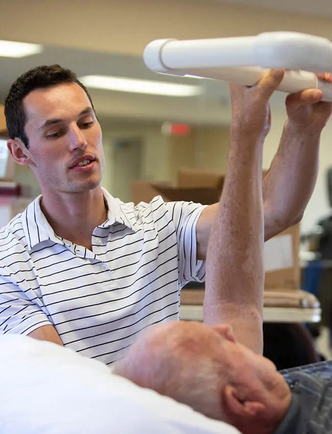 Male physical therapist working with male patient on strength training exercises at Moody Neuro Institute