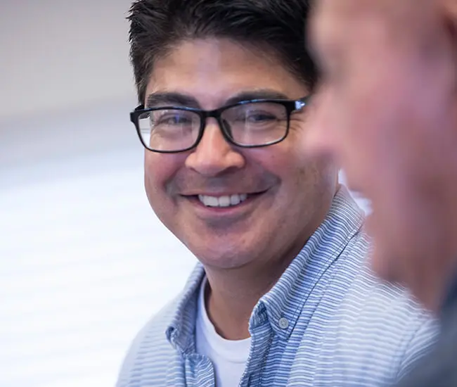 Man with glasses smiling at another male-Moody Neurorehabilitation Institute