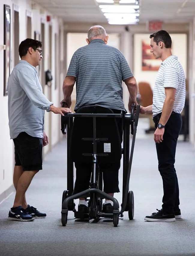 Two male physical therapists working on walking exercises with a male patient at Moody Neurorehabilitation